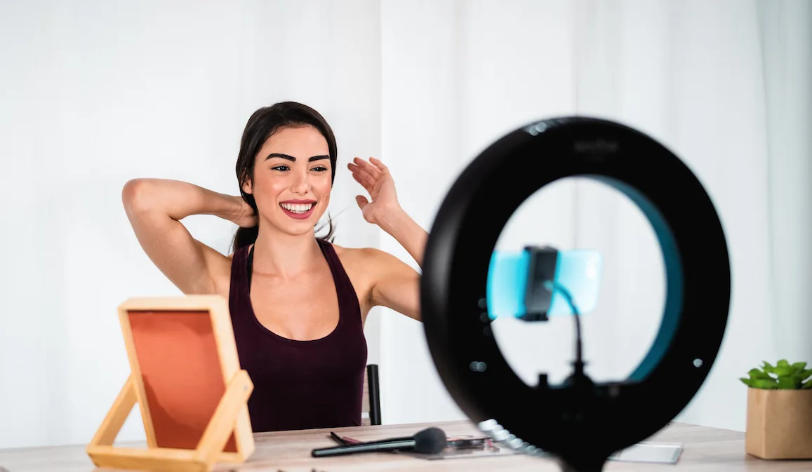 Webcam Model sits behind her phone camera with a ring light
