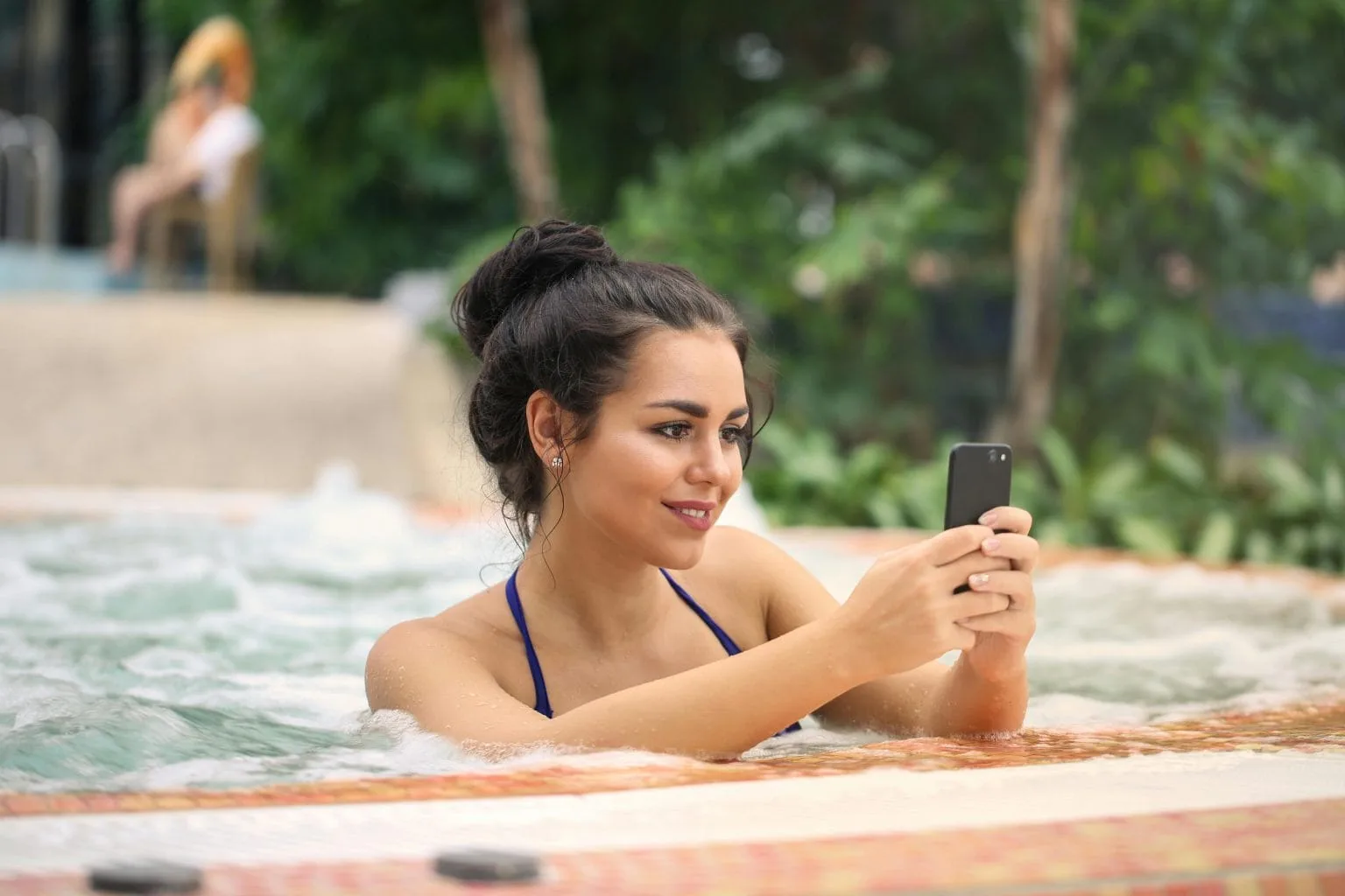 An image of webcam models in the pool, livestreaming on their phones.